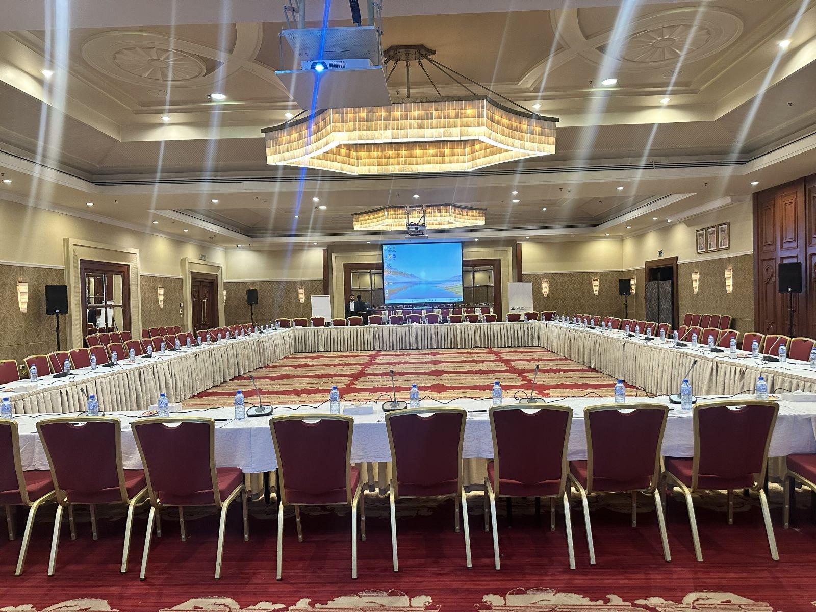 Large U-shaped conference table with projection screen