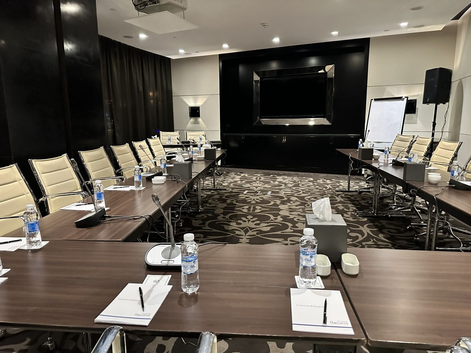 Meeting room prepared with notepads and conference microphones